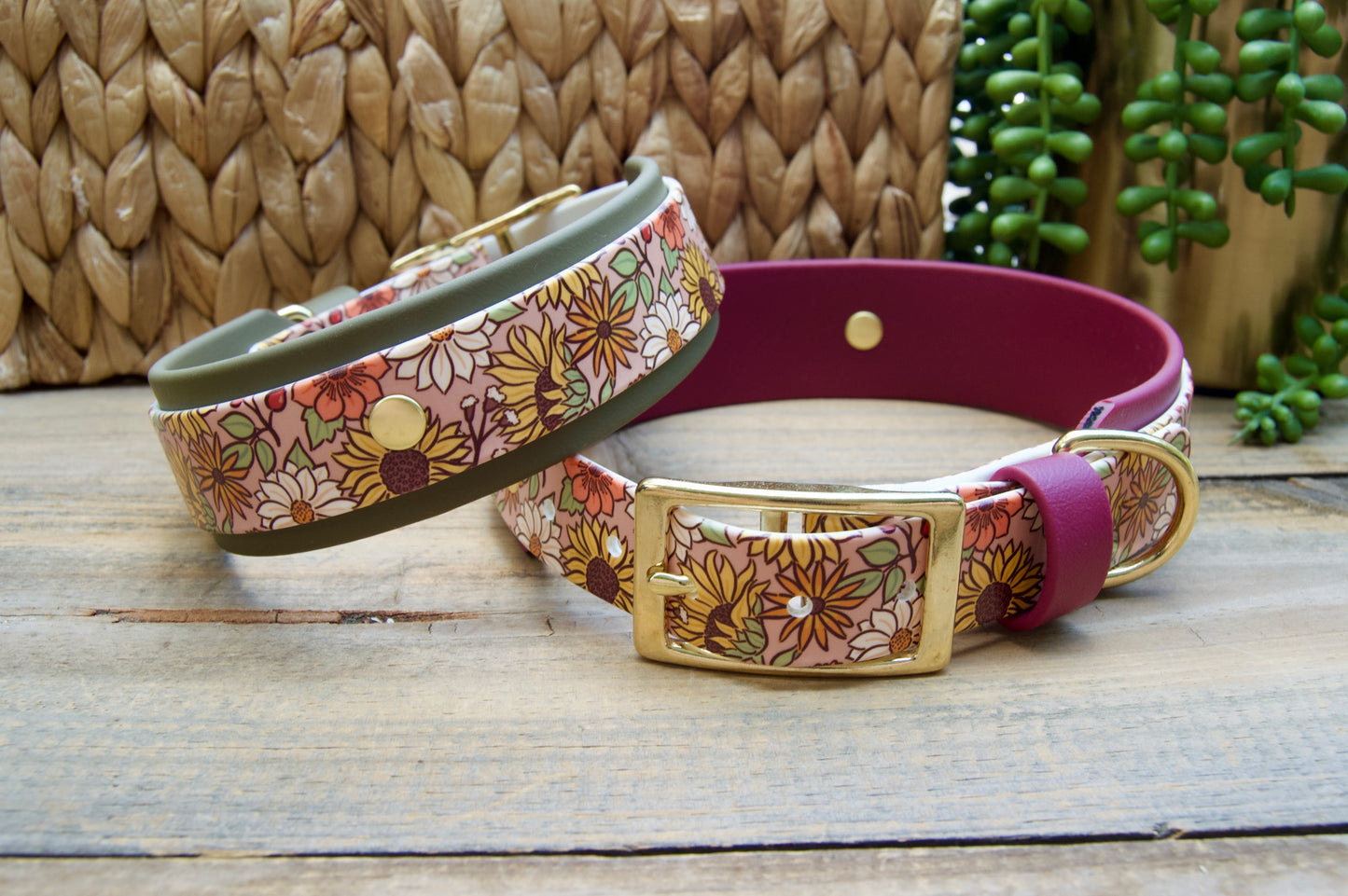 Two dog collars displayed on a rustic wooden surface. One collar has an olive green accent strap the other has a burgundy accent color. Both have a a fall floral pattern and a gold buckle.