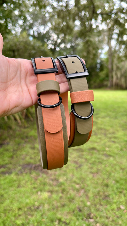 Two Olive Green and Caramel biothane dog collars held by a hand infront of a blurred nature green background