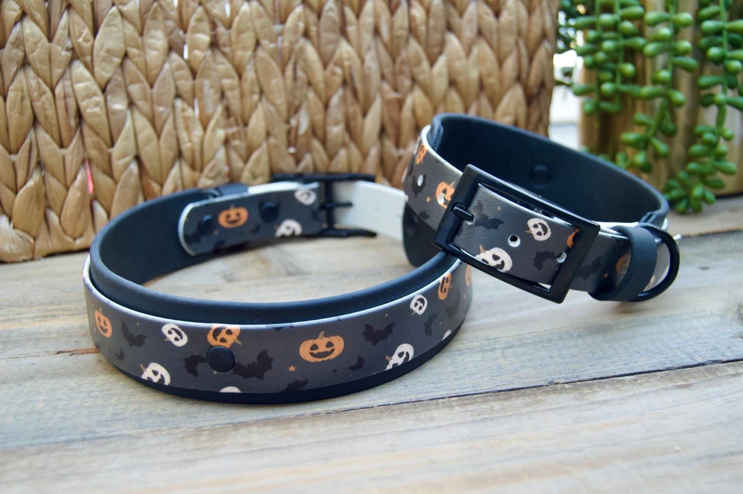 Two Halloween-themed dog collars on a wooden surface with a woven basket background.
